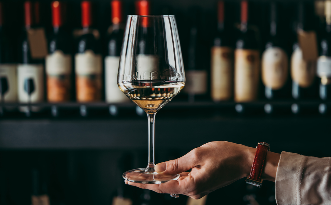 Person holding a glass of white wine