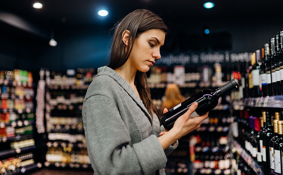 Lady in wine shop reading a label of a bottle