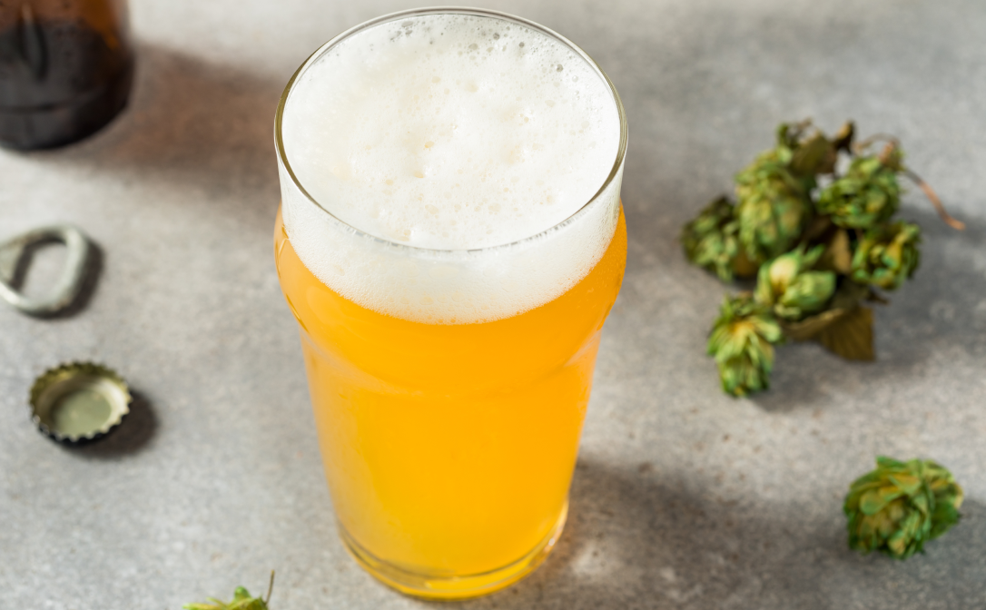 A hazy IPA beer with hops in the background